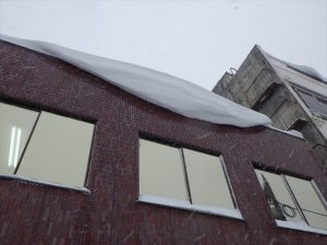 会社の屋根にできた雪庇